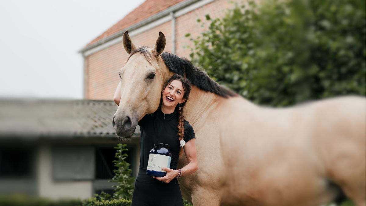 Alizée Froment smiling with her arm around her buckskin horse, holding a jar of Curafyt